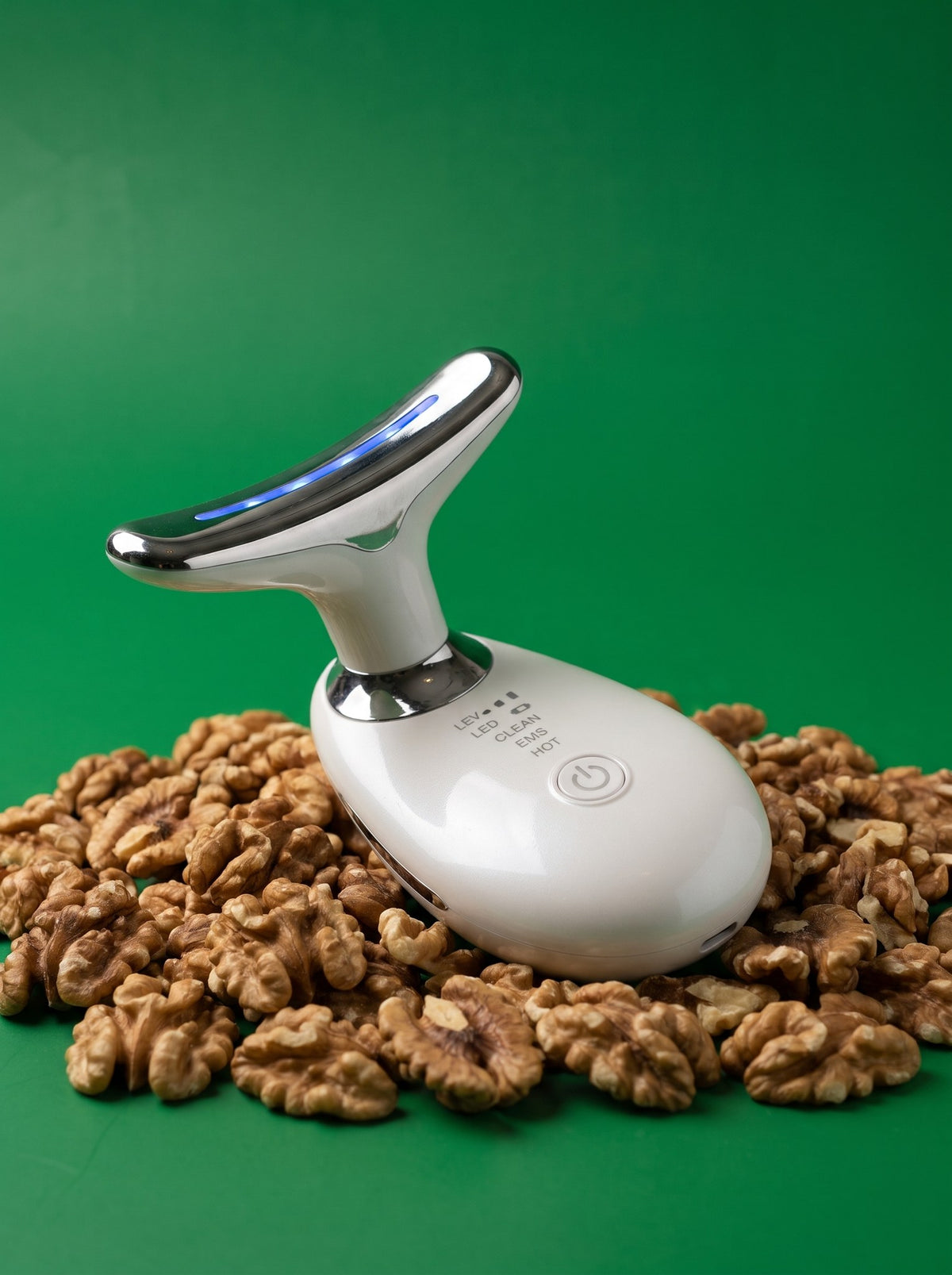 Masajeador facial Contorno blanco sobre un lecho de nueces y fondo verde