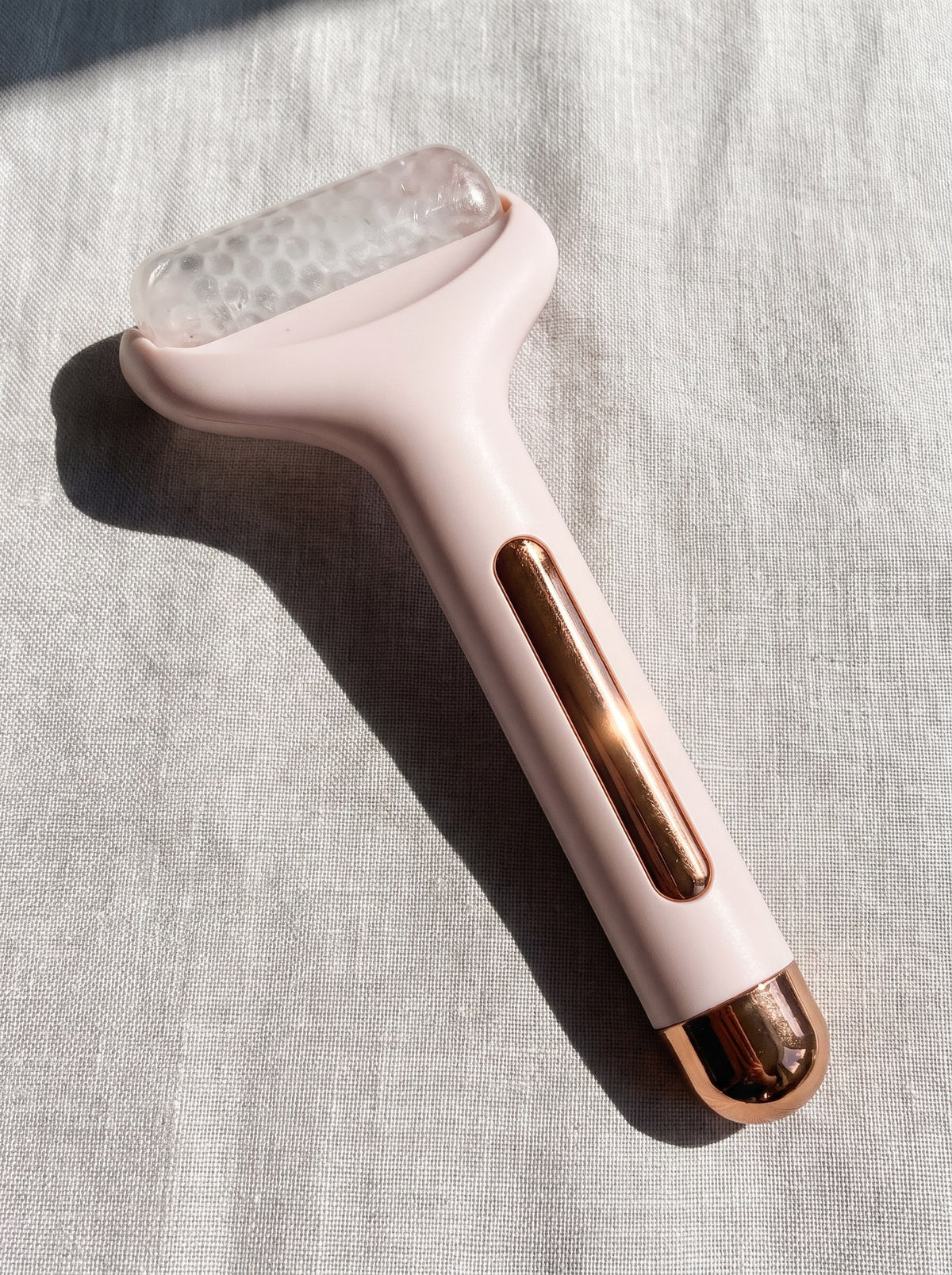 Rodillo de frío facial Escarcha rosa sobre lino claro con luz natural