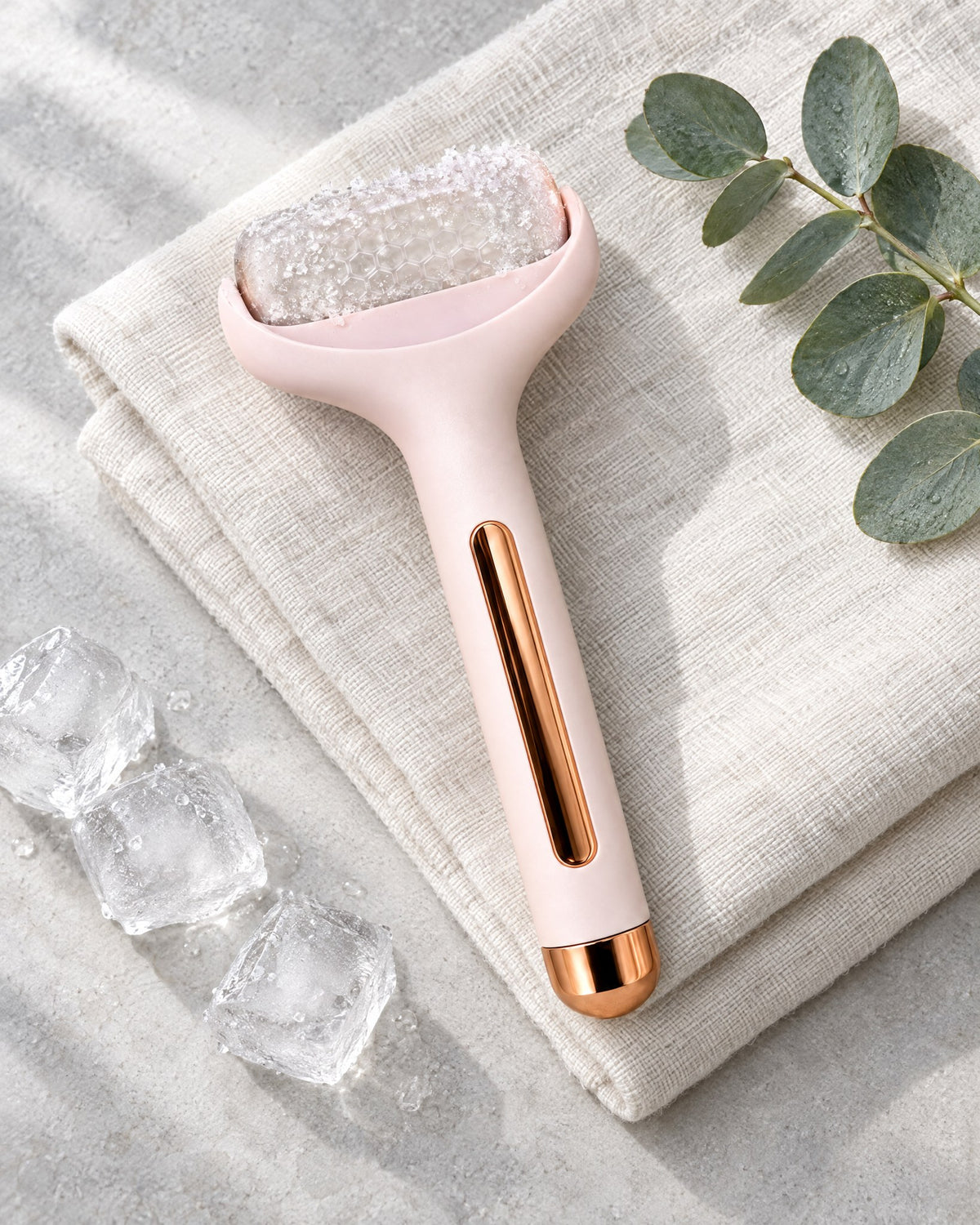 Rodillo de frío facial Escarcha rosa sobre lino blanco con cubitos de hielo y eucalipto