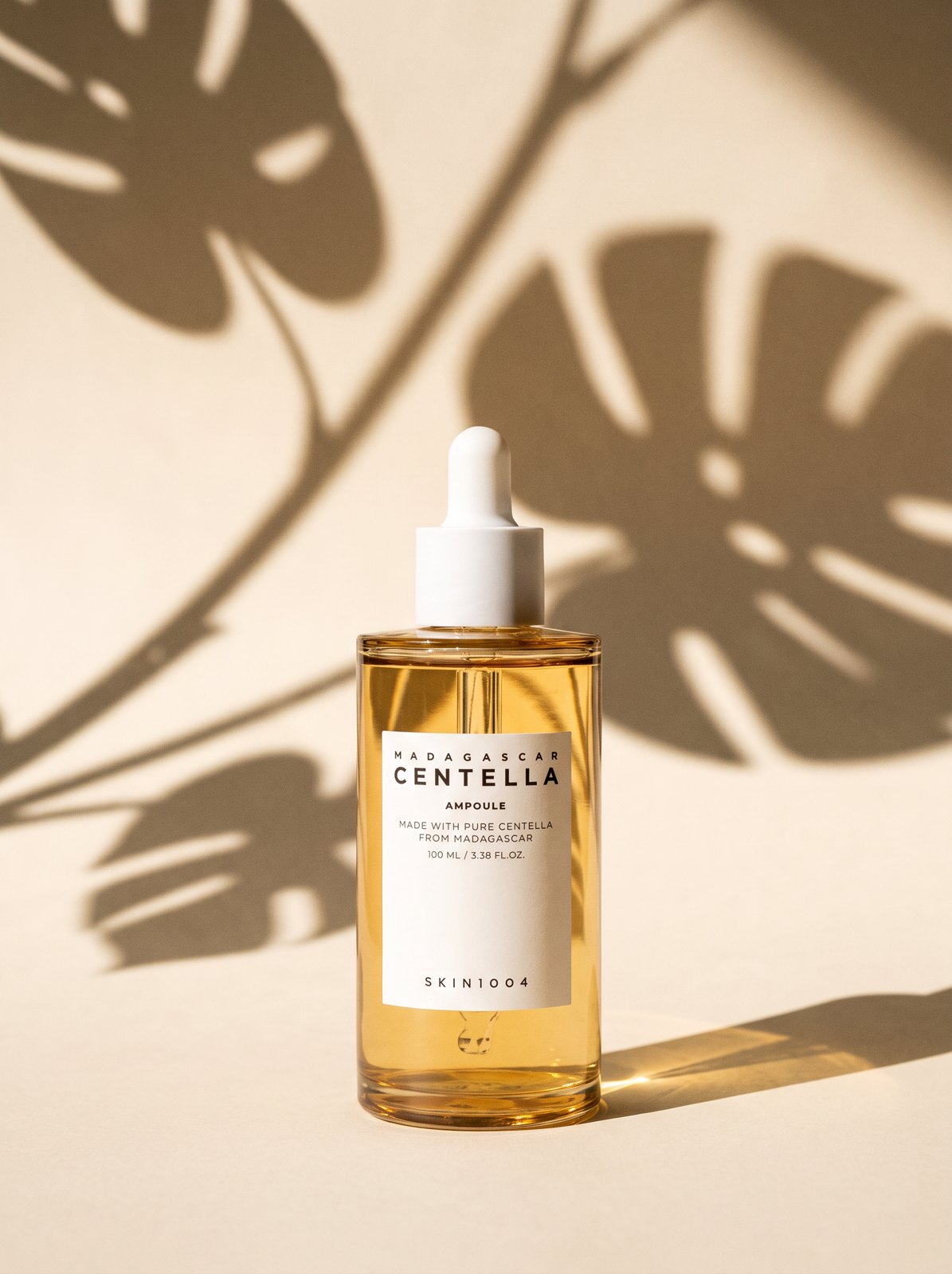 Frasco de SKIN1004 Madagascar Centella Ampoule 100 ml con sombras de hojas