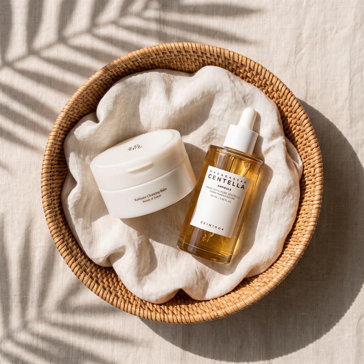 Bálsamo limpiador Beauty of Joseon y sérum SKIN1004 Centella Ampoule en una cesta de ratán con lino